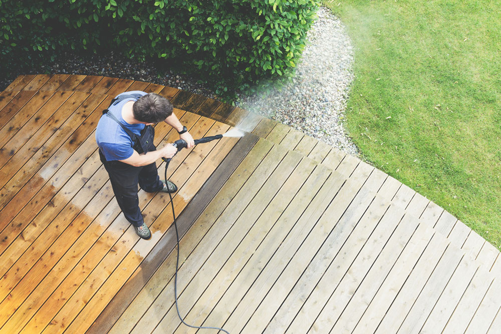 man cleaning terrace with a power washer